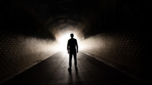 Man walking in dark tunnel - stock photo