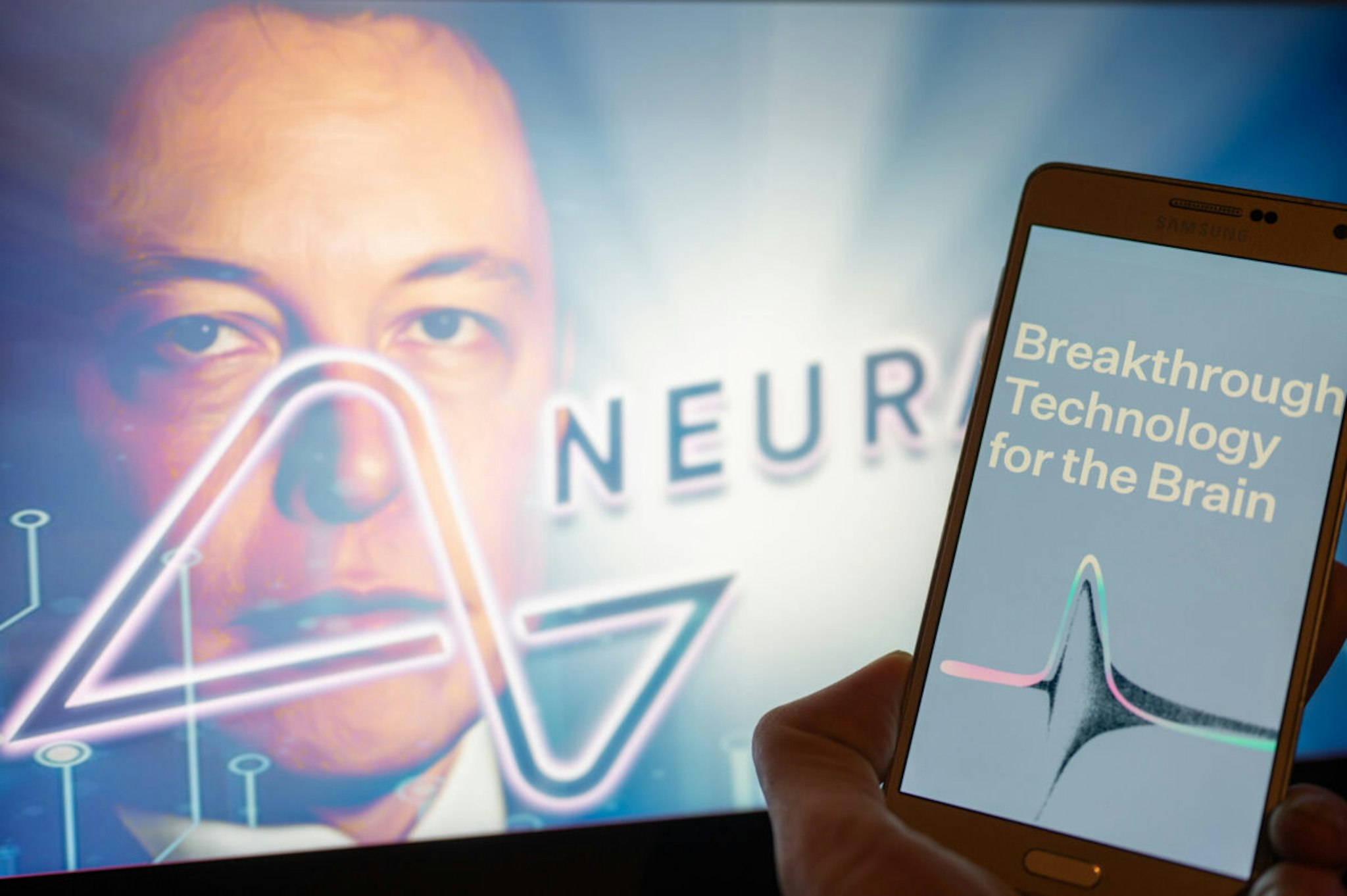Neuralink logo displayed on mobil with founder Elon Musk seen on screen in the background. Neuralink Corporation is a neurotechnology company that develops implantable brain-computer interfaces. In Brussels on 4 December 2022.