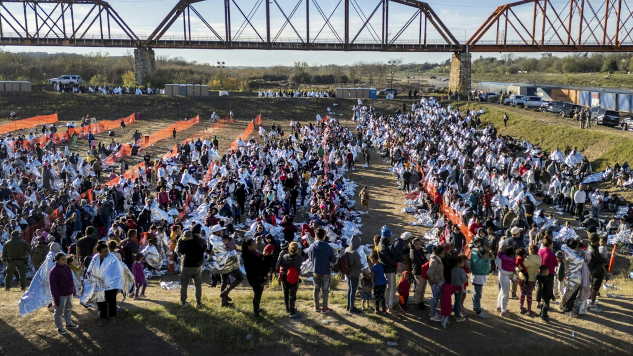 EAGLE PASS, TEXAS - DECEMBER 19: In an aerial view, thousands of immigrants, most wearing thermal blankets, await processing at a U.S. Border Patrol transit center on December 19, 2023 in Eagle Pass, Texas. Major surges of migrants illegally crossing the Rio Grande have overwhelmed U.S. border authorities in recent weeks.