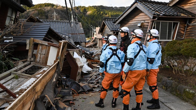 TOPSHOT - Firefighters inspect collapsed wooden houses in Wajima, Ishikawa prefecture on January 2, 2024, a day after a major 7.5 magnitude earthquake struck the Noto region in Ishikawa prefecture in the afternoon. Japanese rescuers battled against the clock and powerful aftershocks on January 2 to find survivors of a major earthquake that struck on New Year's Day, reportedly killing more than 20 people and leaving a trail of destruction.