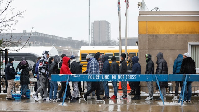 A group of migrants receives food outside the migrant landing zone during a winter storm on January 12, 2024 in Chicago, Illinois. Texas governor Greg Abbott, a staunch Republican, has sought to take the immigration debate nationwide by sending thousands of migrants to Democratic-led northern cities. (Photo by KAMIL KRZACZYNSKI / AFP)