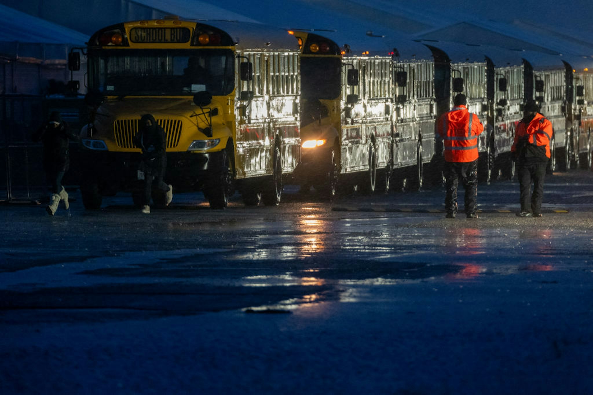 NEW YORK, NEW YORK - JANUARY 09: Nearly 2,000 migrants are evacuated by school buses from tents at Floyd Bennett Field to a local high school in preparation for a storm with estimated wind speeds to be more than 70 mph. on January 09, 2024 in the Brooklyn borough of New York City. Amid the arrival of winter weather, many migrant families are being forced to re-apply for shelter after reaching the 60-day limit for city housing. More than 4,000 families have been served notice on a rolling basis that they will need to re-apply without guarantee of receiving a place. More than 100,000 migrants have arrived in New York City over the last year. (Photo by Spencer Platt/Getty Images)