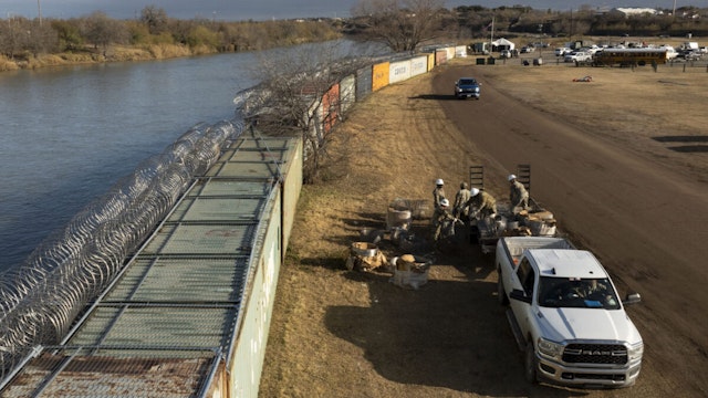 EAGLE PASS, TEXAS - JANUARY 26: In an aerial view, Texas National Guard soldiers load excess concertina wire onto a trailer at Shelby Park on January 26, 2024 in Eagle Pass, Texas.