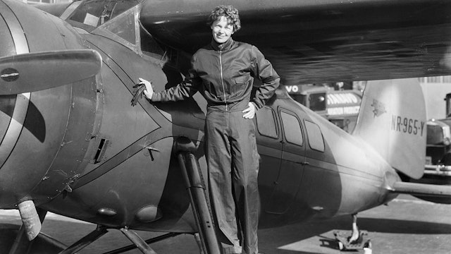 (Original Caption) Amelia Earhart (1898-1937), American aviatrix, first woman to cross Atlantic. Photograph showing her with airplane.