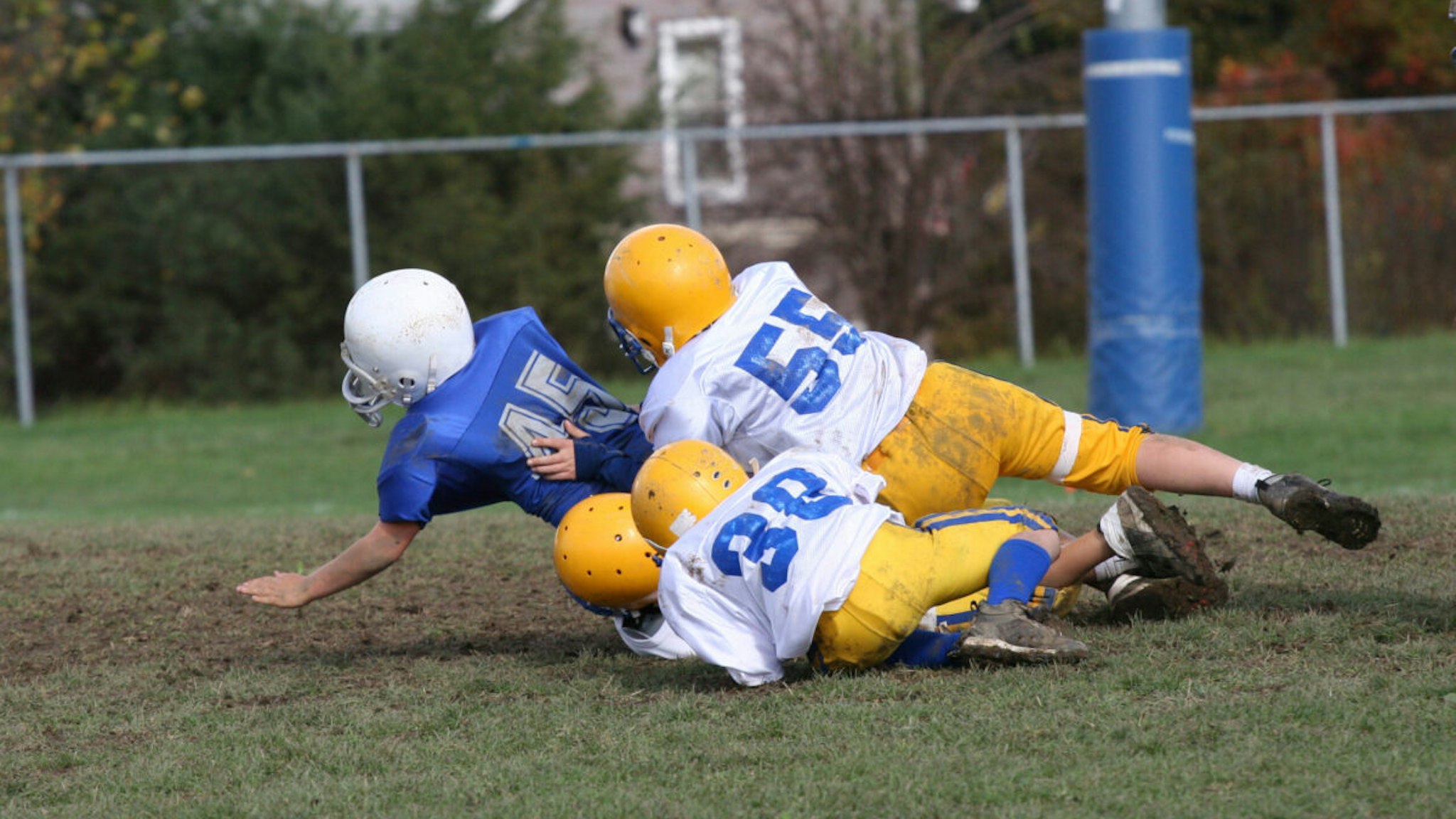 Football tackle at youth game during the day.