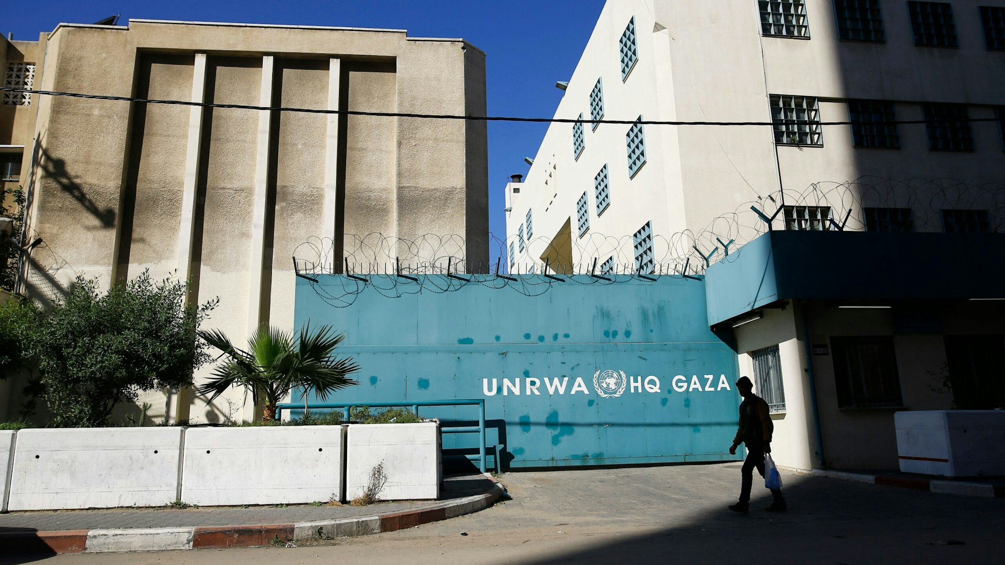 A Palestinian man walks past the building of the UNRWA headquarters in Gaza City on January 8, 2018. - Israeli Prime Minister Benjamin Netanyahu called for the closure of the United Nations agency for Palestinian refugees, days after US President Donald Trump threatened to cut Palestinian aid.