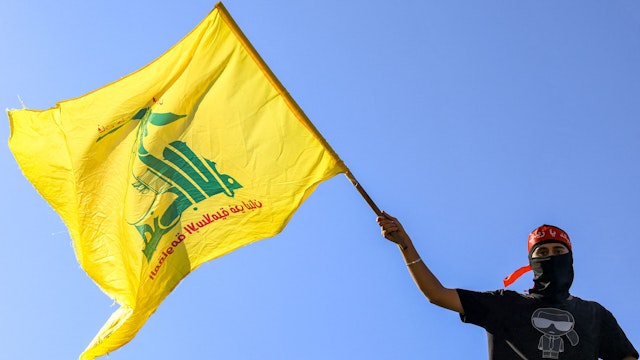 A masked demonstrator waves a flag of the Lebanese Shiite movement Hezbollah during a demonstration supporting the Palestinians in Beirut on October 20, 2023, amid the ongoing battles between Israel and the Palestinian group Hamas.