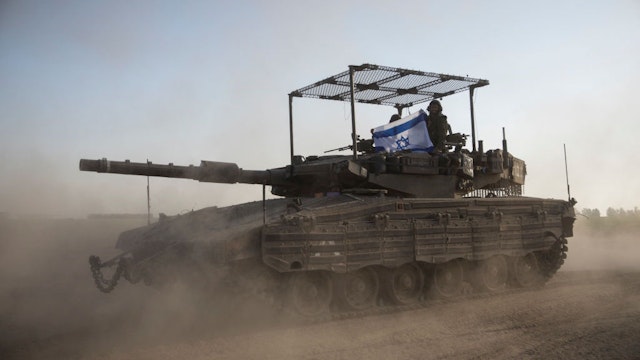 Israeli soldiers hold an Israeli flag on a tank that is moving along the border with Gaza Strip on January 21, 2024 in Southern Israel, Israel. (Photo by Amir Levy/Getty Images)