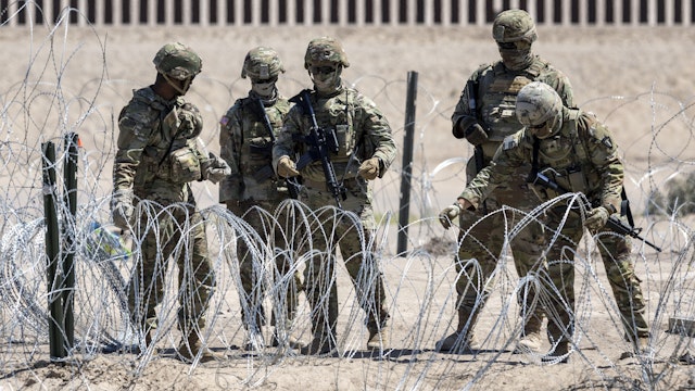 EL PASO, TEXAS - MAY 11: Texas National Guard soldiers close a section of razor wire surrounding a makeshift migrant camp on May 11, 2023 in El Paso, Texas. The number of immigrants reaching the border has surged with the end of the U.S. government's Covid-era Title 42 policy, which for the past three years has allowed for the quick expulsion of irregular migrants entering the country.