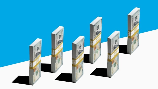6 bundles of US $100 bills standing vertically near edge of white shelf, blue background