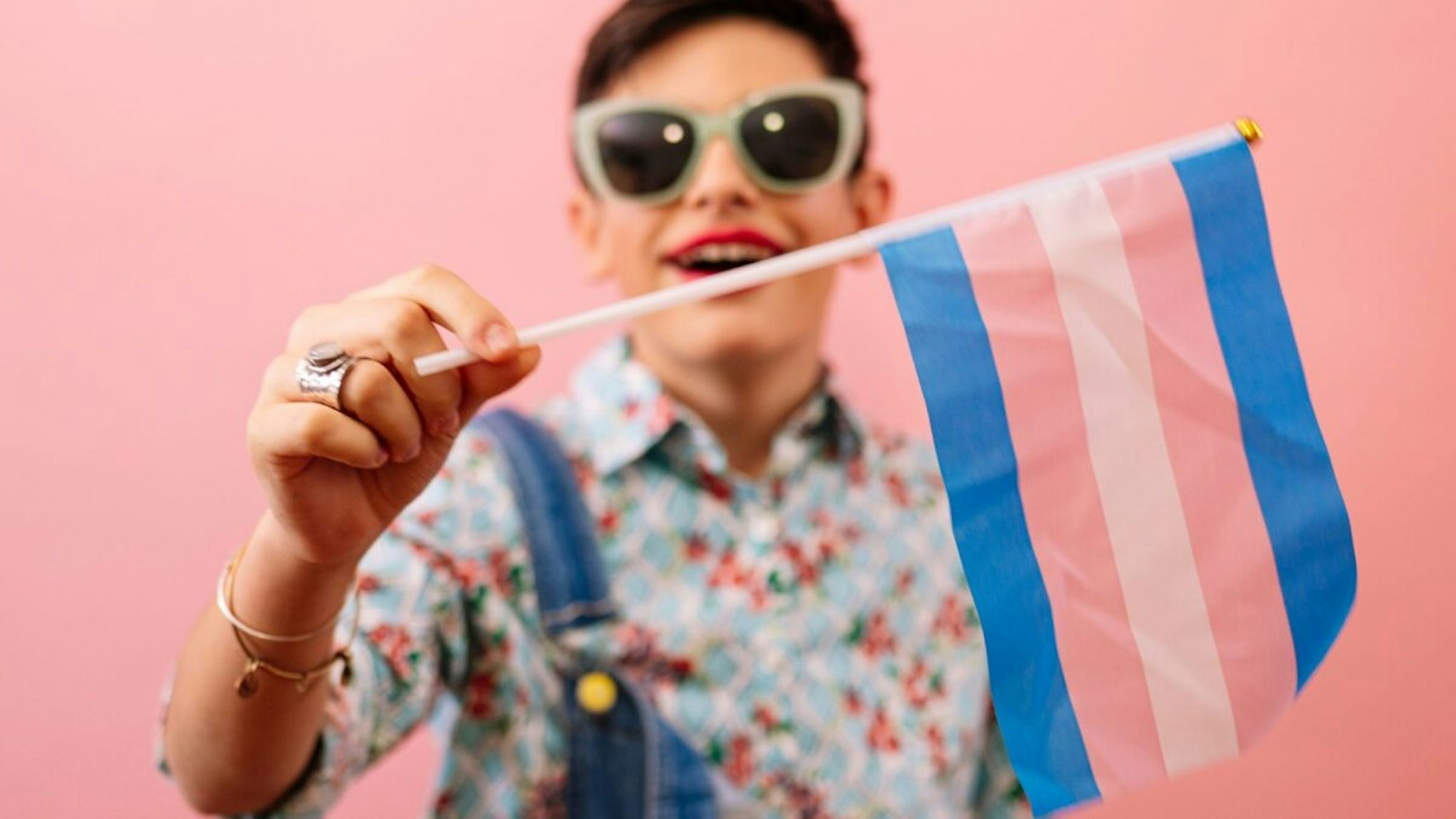 Young boy feeling girly and holding a trans flag.