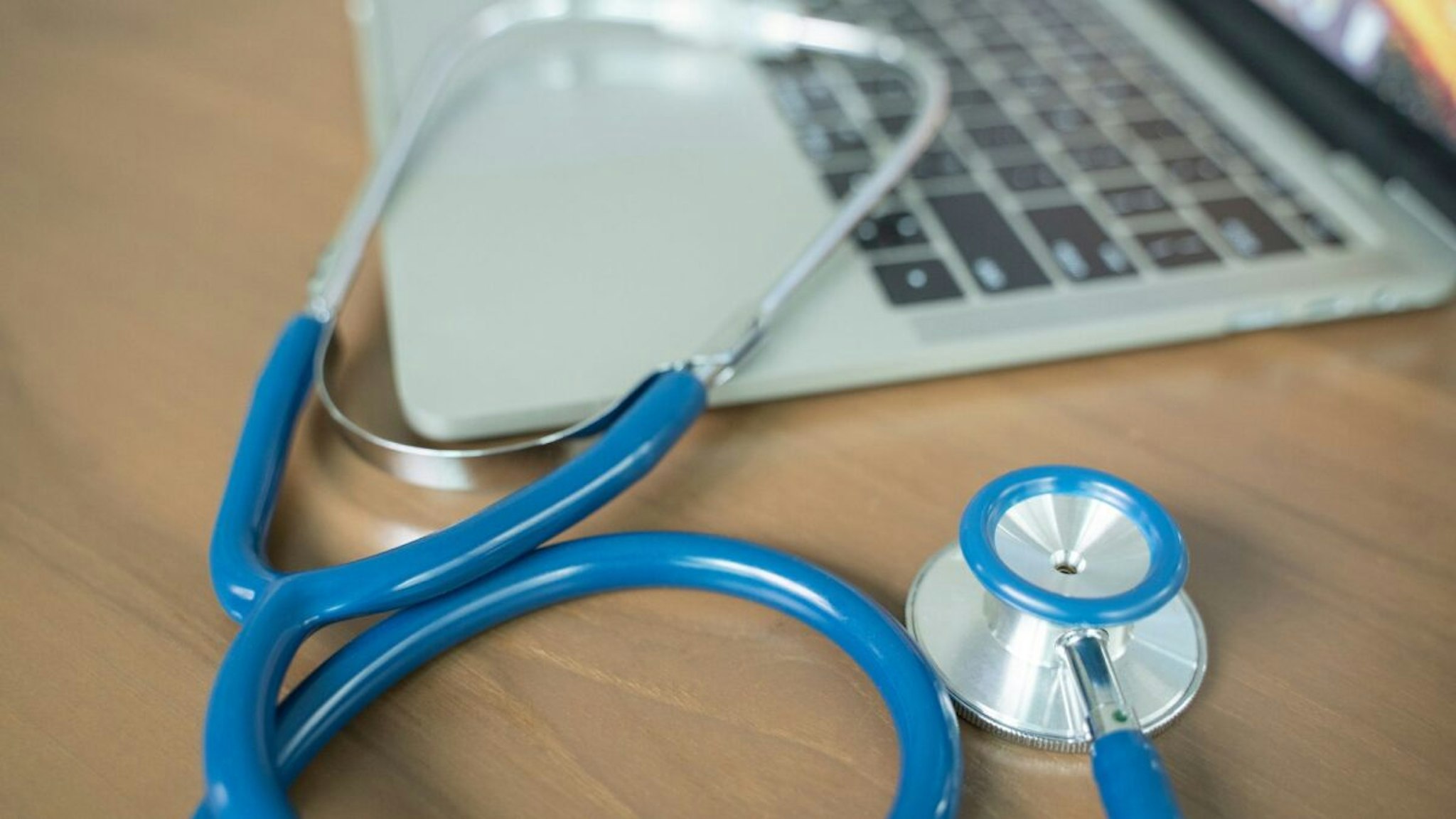 Doctor's desk with stethoscope and laptop. - stock photo
