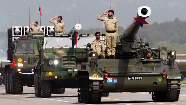 Pakistani soldiers salute atop stand a tank (R) and army vehicles during the Pakistan Day parade in Islamabad on March 23, 2022.