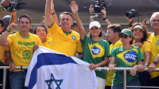 Former Brazilian President Jair Bolsonaro (C-L) greets supporters next to his wife Michelle Bolsonaro (C-R) during a rally in Sao Paulo, Brazil, on February 25, 2024, to reject claims he plotted a coup with allies to remain in power after his failed 2022 reelection bid. Investigators say the far-right ex-army captain led a plot to falsely discredit the Brazilian election system and prevent the winner of the vote, leftist President Luiz Inacio Lula da Silva, from taking power. A week after Lula took office on January 1, 2023, thousands of Bolsonaro supporters stormed the presidential palace, Congress and Supreme Court, urging the military to intervene to overturn what they called a stolen election.