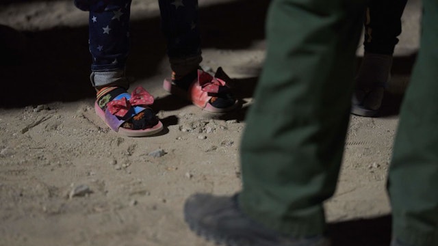 TOPSHOT - A girl (detail shoes) waits to be processed by US Border Patrol agent (detail shoe) after illegally crossing the US-Mexico border in Yuma, Arizona in the early morning of July 11, 2022. - Every year, tens of thousands of migrants fleeing violence or poverty in Central and South America attempt to cross the border into the United States in pursuit of the American dream. Many never make it. (Photo by allison dinner / AFP) (Photo by ALLISON DINNER/AFP via Getty Images)