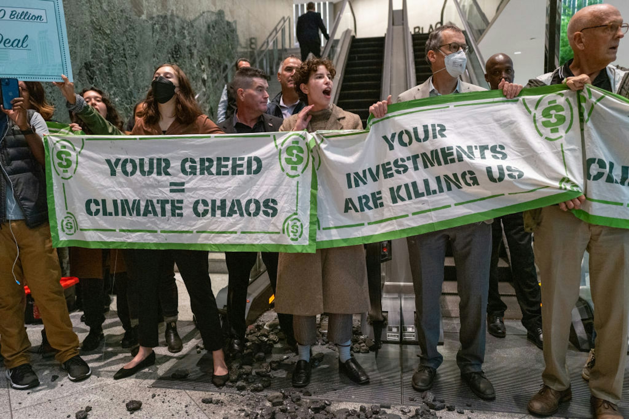 NEW YORK, NEW YORK - OCTOBER 26: Climate activists block an escalator and throw coal on the ground at the New York headquarters of the financial investment firm BlackRock on October 26, 2022 in New York City. The activists, who have been holding protests to mark 10 years sine Hurricane Sandy, were protesting the company's investment in fossil fuels.