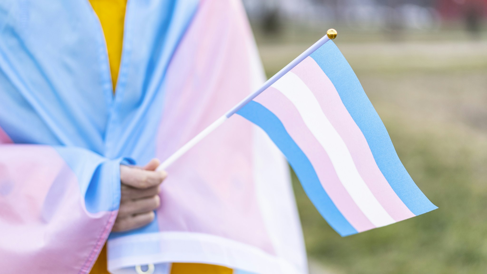 Transgender covered with the transgender flag and holding a flag in the hand for defending her rights