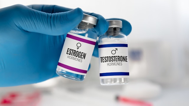 Hand of doctor with two injection vials for treatment with Testosterone and Estrogen hormones. Doctor With bottles for Testosterone and Estrogen hormonal balance therapy