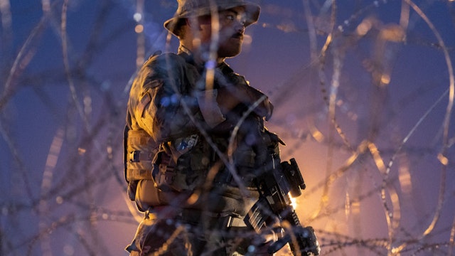 EL PASO, TEXAS - MAY 11: A Texas National Guard soldier stands vigil at a makeshift migrant camp near the U.S.-Mexico border fence on May 11, 2023 in El Paso, Texas. A surge of immigrants is expected with today's end of the U.S. government's Covid-era Title 42 policy, which for the past three years has allowed for the quick expulsion of irregular migrants entering the country. About 25,000 immigrants are currently in the custody of U.S. Customs and Border Protection with the sunset of the policy tonight. (Photo by John Moore/Getty Images)