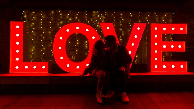 Raina Kuan and Levi Swanky kiss in front of LED marquee letters that read, "LOVE" during Love Lights at Capilano Suspension Bridge Park ahead of Valentine's Day on February 12, 2022 in North Vancouver, British Columbia, Canada.