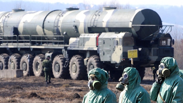 Russian soldiers wear chemical protection suits as they stand next to a military fueler on the base of a prime mover of Russian Topol intercontinental ballistic missile during a training session at the Serpukhov's military missile forces research institute some 100km outside Moscow on April 6, 2010. The US-Russia nuclear arms treaty to be signed this week enhances trust between the Cold War foes but Moscow may quit the pact if US missile defence plans go too far, a top Russian official said Tuesday.