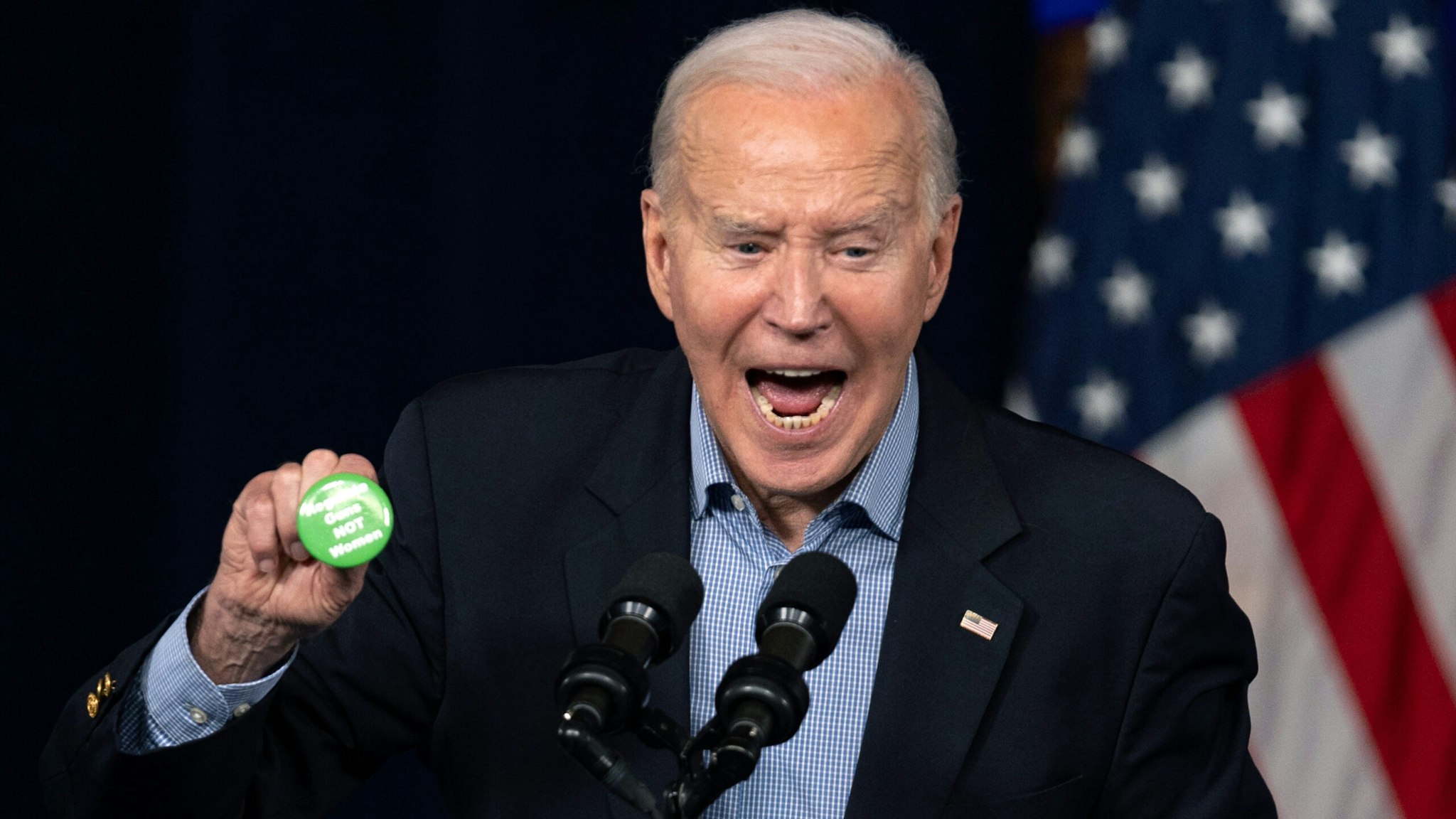 ATLANTA, GEORGIA - MARCH 9: President Joe Biden picks up a button thrown on stage that reads "Regulate Guns not Women" during a campaign event at Pullman Yards on March 9, 2024 in Atlanta, Georgia. President Biden and Former President Donald Trump are both campaigning in Georgia today ahead of the Primary election voting taking place on Tuesday.