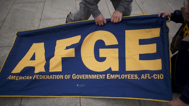 Members of the AFGE (American Federation of Government Employees) set up a banner during a protest. (Photo by Mark Makela/Getty Images)
