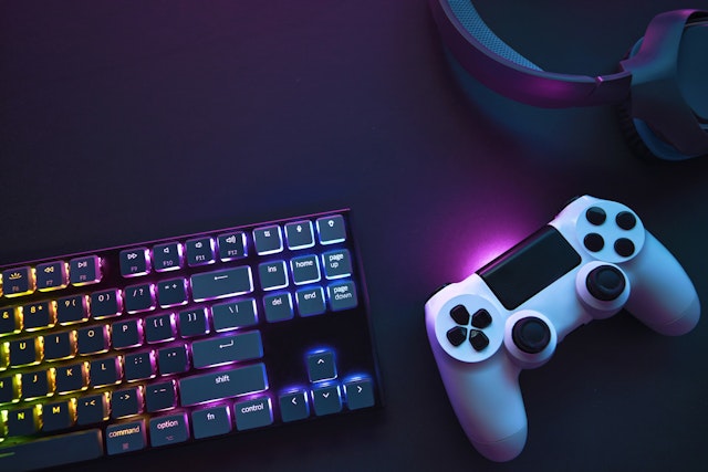Top down view of colorful illuminated gaming accessories laying on table. Professional computer game playing, esport business and online world concept.