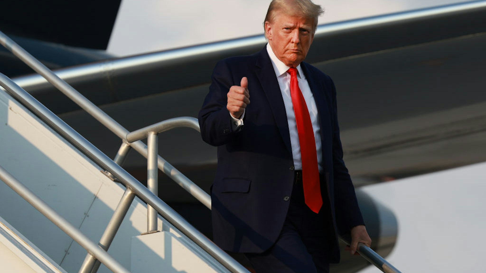 ATLANTA, GEORGIA - AUGUST 24: Former U.S. President Donald Trump gives a thumbs up as he arrives at Atlanta Hartsfield-Jackson International Airport on August 24, 2023 in Atlanta, Georgia. Trump is expected to surrender at the Fulton County jail, where he will be booked on 13 charges related to an alleged plan to overturn the results of the 2020 presidential election in Georgia.