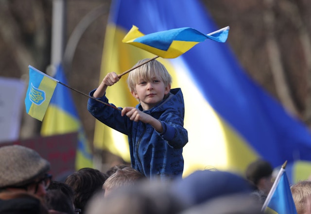 BERLIN, GERMANY - FEBRUARY 24: A young boy waves Ukrainian flags among people demonstrating at the Brandenburg Gate to show solidarity with Ukraine on the second anniversary of Russia's invasion of Ukraine on February 24, 2024 in Berlin, Germany. The war has recently seen Russian forces take the upper hand and begin to move forward in eastern Ukraine as Ukrainian forces face critical shortages of munitions. (Photo by Sean Gallup/Getty Images)