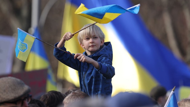 BERLIN, GERMANY - FEBRUARY 24: A young boy waves Ukrainian flags among people demonstrating at the Brandenburg Gate to show solidarity with Ukraine on the second anniversary of Russia's invasion of Ukraine on February 24, 2024 in Berlin, Germany. The war has recently seen Russian forces take the upper hand and begin to move forward in eastern Ukraine as Ukrainian forces face critical shortages of munitions. (Photo by Sean Gallup/Getty Images)