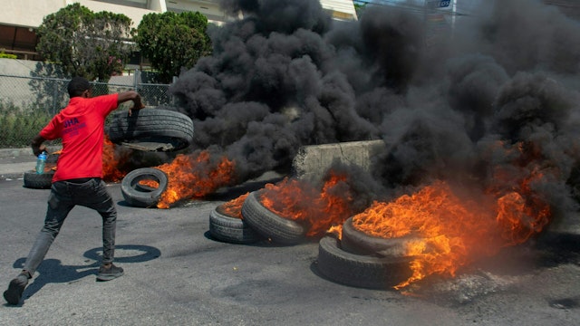 A protester burns tires during a demonstration following the resignation of its Prime Minister Ariel Henry, in Port-au-Prince, Haiti, on March 12, 2024. A political transition deal in Haiti marks a key step forward for the violence-ravaged country but far more needs to be done, with some experts warning the situation could deteriorate further.