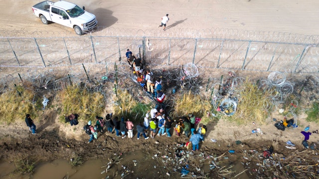 EL PASO, TEXAS - MARCH 13: In an aerial view, immigrants pass through coils of razor wire while crossing the U.S.-Mexico border on March 13, 2024 in El Paso, Texas. The wire was placed by the troops as part of Texas Governor Greg Abbott's "Operation Lone Star" to deter migrants from crossing into Texas. The vast majority of immigrants, however, manage to pass through it, and are then permitted to turn themselves in to U.S. Border Patrol agents, usually to request asylum. The border between the two nations stretches nearly 2,000 miles, from the Gulf of Mexico to the Pacific Ocean and is marked by fences, deserts, mountains and the Rio Grande, which runs the entire length of Texas. The politics and controversies surrounding border and immigration issues have become dominant themes in the U.S. presidential election campaign. (Photo by John Moore/Getty Images)