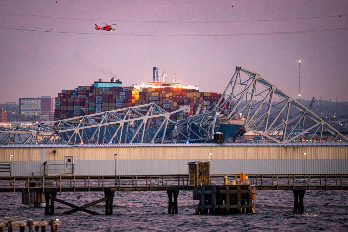 A US Coast Guard helicopter flies over the Dali container vessel after it struck the Francis Scott Key Bridge that collapsed into the Patapsco River in Baltimore, Maryland, US, on Tuesday, March 26, 2024. The commuter bridge collapsed after being rammed by the Dali ship, causing vehicles to plunge into the water.