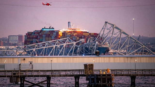 A US Coast Guard helicopter flies over the Dali container vessel after it struck the Francis Scott Key Bridge that collapsed into the Patapsco River in Baltimore, Maryland, US, on Tuesday, March 26, 2024. The commuter bridge collapsed after being rammed by the Dali ship, causing vehicles to plunge into the water.