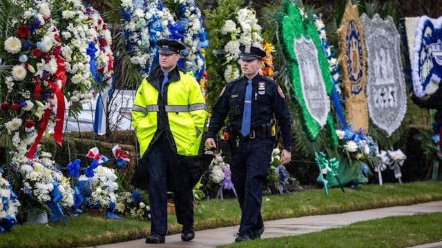 Massapequa Park, N.Y.: Two police officers walk past flowers on display for the Wake of New York Police Department Officer Jonathan Diller at Massapequa Funeral Home in Massapequa Park, New York, on March 28, 2024.