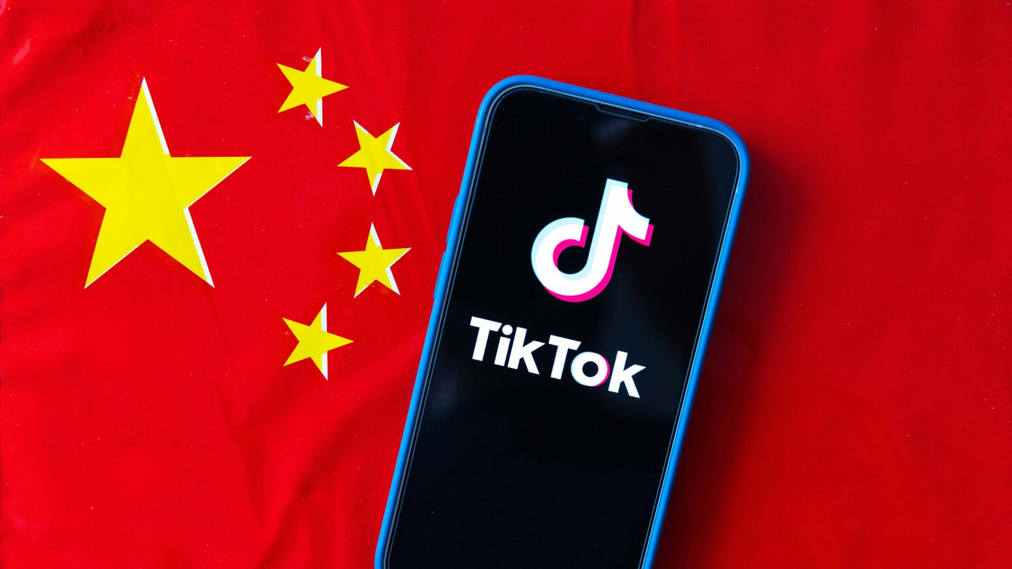 JAPAN - 2023/04/16: In this photo illustration, mobile phone displays TikTok logo with the flag of the People's Republic of China in the background.