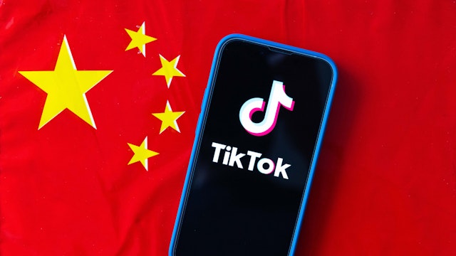 JAPAN - 2023/04/16: In this photo illustration, mobile phone displays TikTok logo with the flag of the People's Republic of China in the background.