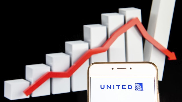 HONG KONG - 2018/12/15: In this photo illustration, the American airline United Airlines logo is seen displayed on an Android mobile device with a decline loses graph in the background.