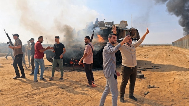 TOPSHOT - Palestinians take control of an Israeli Merkava battle tank after crossing the border fence with Israel from Khan Yunis in the southern Gaza Strip on October 7, 2023. Barrages of rockets were fired at Israel from the Gaza Strip at dawn as militants from the blockaded Palestinian enclave infiltrated Israel, with at least one person killed, the army and medics said.