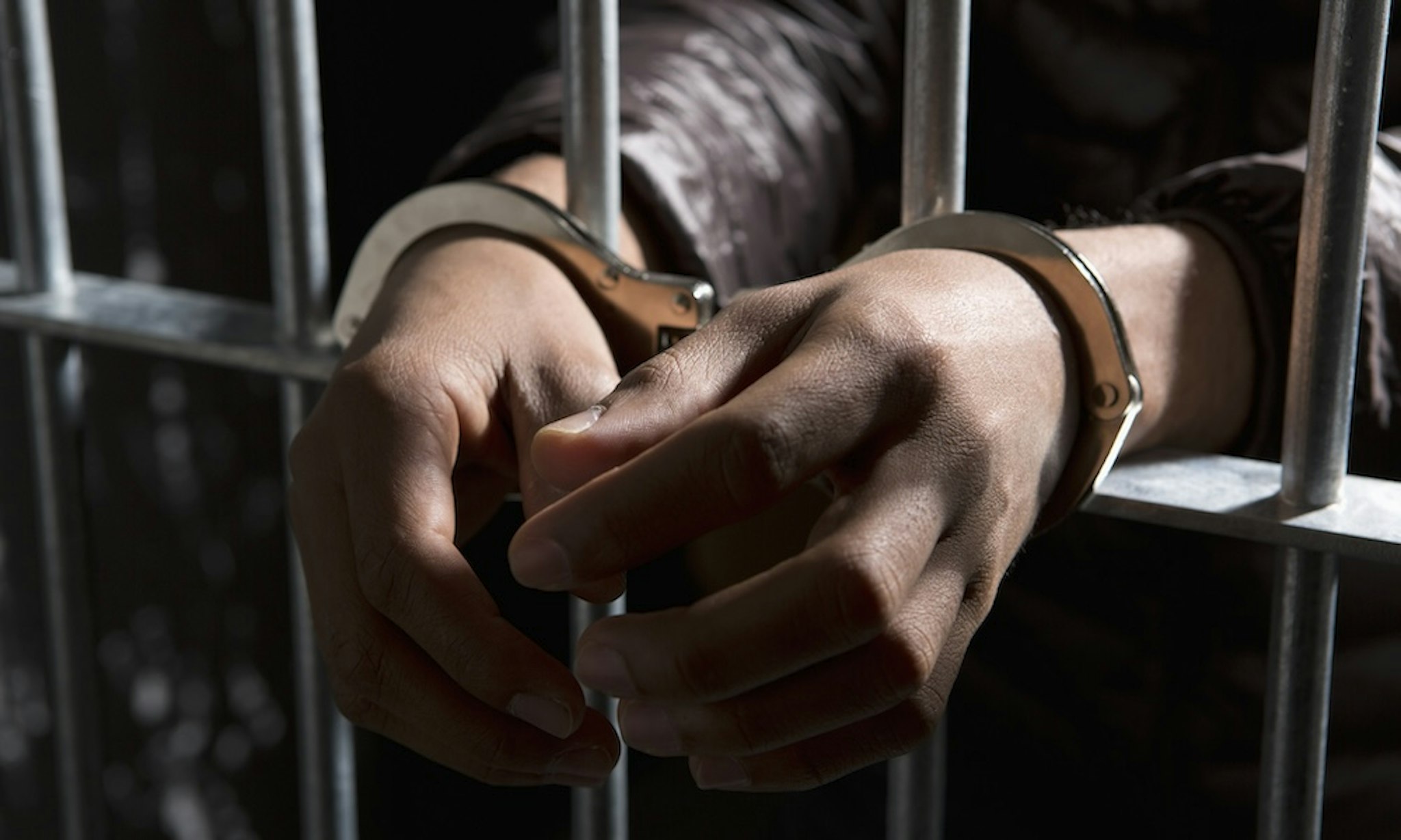 A prisoner behind bars with hands cuffed -- Caspar Benson via Getty Images
