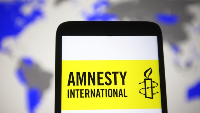 In this photo illustration an Amnesty International (AI) logo is seen on a smartphone screen.