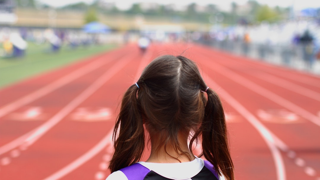 "A picture of a youth girl at the starting line, about to compete in a track &amp; field event."