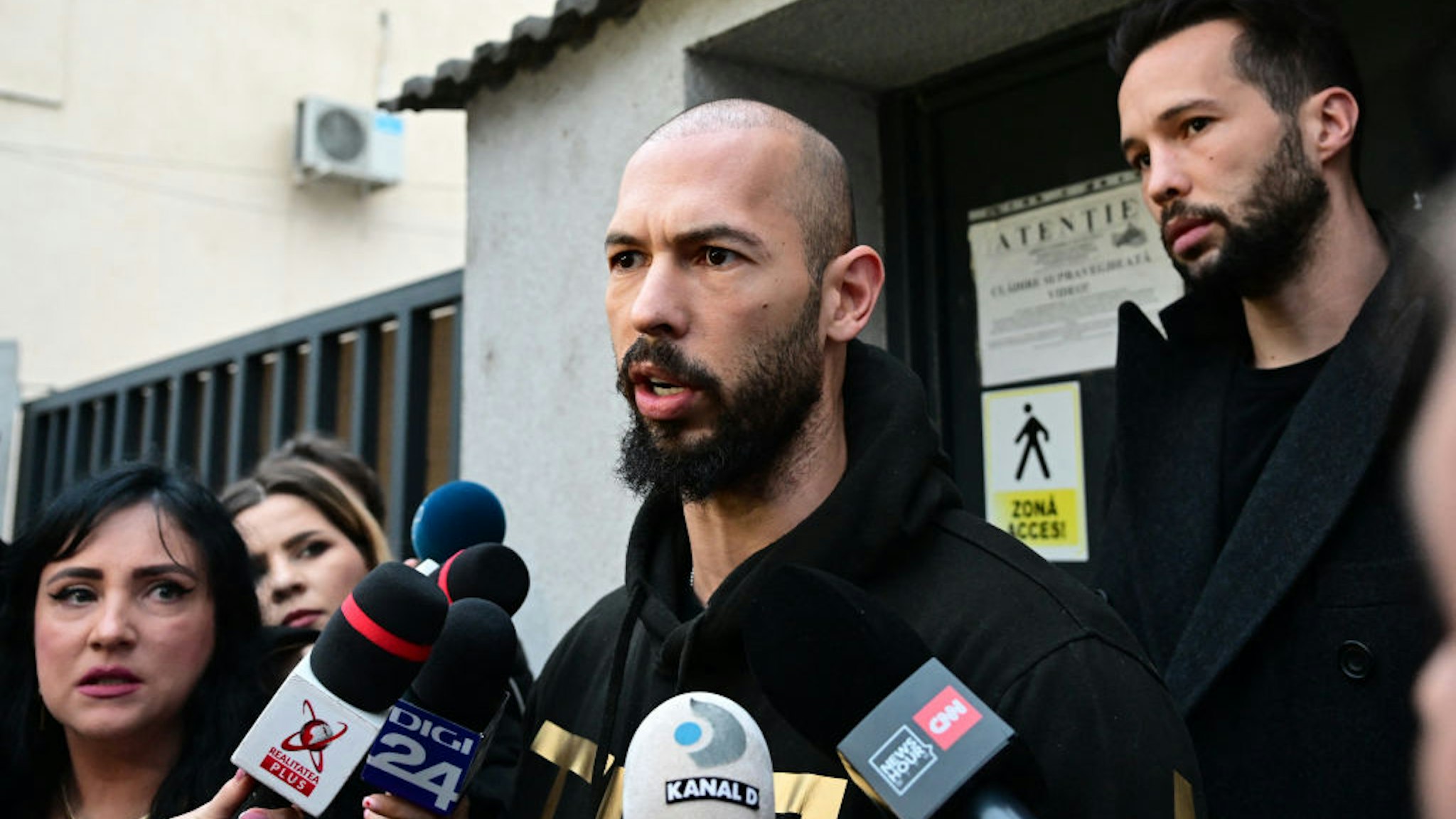British-US former professional kickboxer and controversial influencer Andrew Tate (C) and his brother Tristan Tate (R) speak to journalists after having been released from detention in Bucharest, Romania on March 12, 2024, after they appeared in a court after Romanian police detained them over UK sex offence charges. A Bucharest court on March 12 granted a request to extradite controversial influencer Andrew Tate to the UK over sex offence charges, but only after the conclusion of legal proceedings in Romania in a separate case. The Bucharest appeals court ruling "orders the execution of the warrant of arrest issued on 19 January 2024" by the Westminster Magistrates' Court, but postpones extradition "until the final resolution of the case" in Romania, which could take years. (Photo by Daniel MIHAILESCU / AFP) (Photo by DANIEL MIHAILESCU/AFP via Getty Images)
