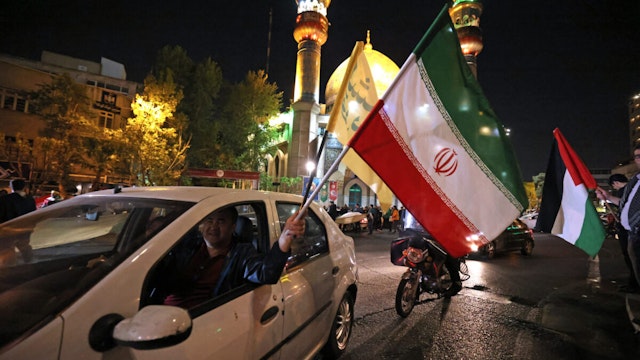 Demonstrators wave Iran's flag and a Palestinian flag as they gather at Palestine Square in Tehran on April 14, 2024, after Iran launched a drone and missile attack on Israel. Iran's Revolutionary Guards confirmed early April 14, 2024 that a drone and missile attack was under way against Israel in retaliation for a deadly April 1 drone strike on its Damascus consulate.