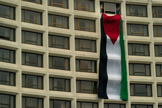 WASHINGTON, DC - APRIL 27: Demonstrators hand a Palestinian flag from a room at the Washington Hilton, the site of the Annual White House Correspondents Dinner, on April 27, 2024 in Washington, DC. President Joe Biden is attending the event where demonstrators are attempting to blockade the entrance in protest of the Biden administration's continued support of Israel despite the calls for a cease fire between Israel and Hamas. (Photo by Kent Nishimura/Getty Images)
