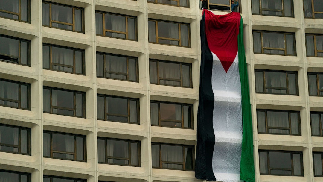 WASHINGTON, DC - APRIL 27: Demonstrators hand a Palestinian flag from a room at the Washington Hilton, the site of the Annual White House Correspondents Dinner, on April 27, 2024 in Washington, DC. President Joe Biden is attending the event where demonstrators are attempting to blockade the entrance in protest of the Biden administration's continued support of Israel despite the calls for a cease fire between Israel and Hamas. (Photo by Kent Nishimura/Getty Images)