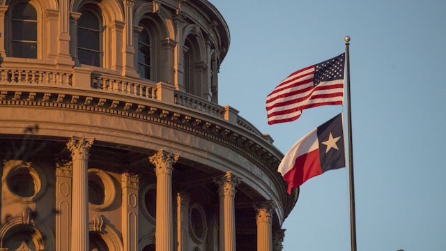 An American flag flies with the Texas state flag outside the Texas State Capitol building in Austin, Texas, U.S., on Tuesday, March 14, 2017. Austin has spent the last 10 months engaged in a big experiment in urban transportation. Several hundreds of thousands of people will descend upon Austin for the annual South by Southwest festival, a nine-day event that could be described as a tech conference, a music and film festival.