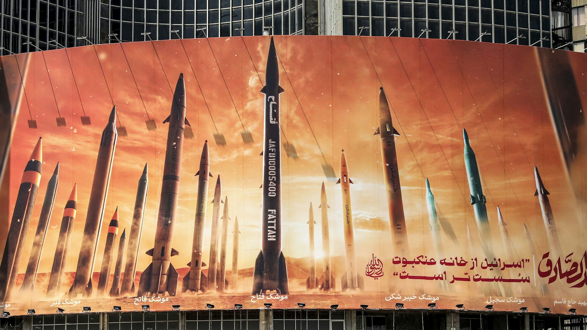 This picture taken on April 15, 2024 shows a view of a billboard depicting named Iranian ballistic missiles in service, with text in Arabic reading "the honest [person's] promise" and in Persian "Israel is weaker than a spider's web", in Valiasr Square in central Tehran. Iran on April 14 urged Israel not to retaliate militarily to an unprecedented attack overnight, which Tehran presented as a justified response to a deadly strike on its consulate building in Damascus.