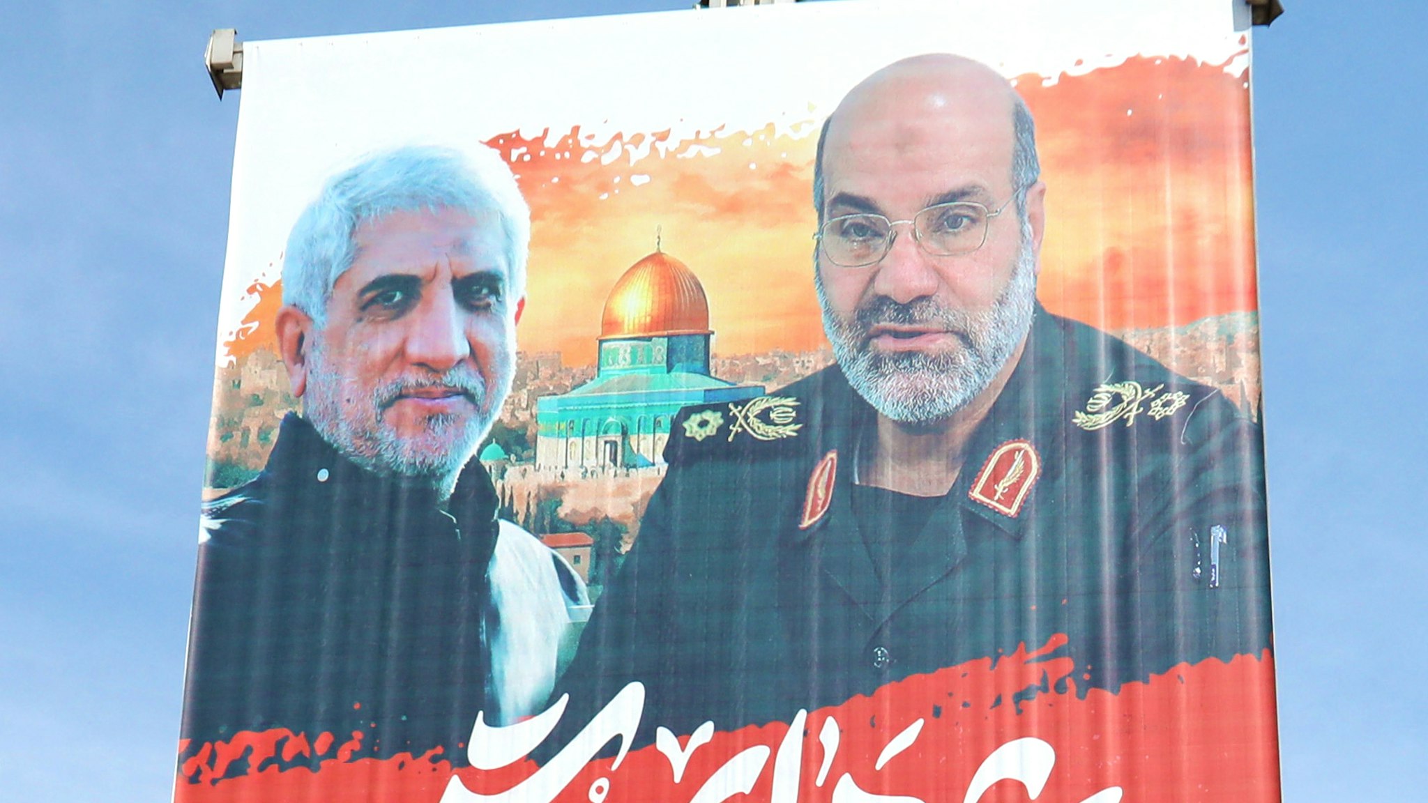 People walk past portraits of slain Brigadier General Mohammad Reza Zahedi's and Mohammad Hadi Haji Rahimi written "Martyrs of Quds" (Jerusalem), on April 3, 2024 in Tehran, after they were killed in a strike at the consular annex of the Iranian embassy in Damascus. On April 1 afternoon, Israeli strikes targeted the consular annex of Iran's embassy, killing at least 13 people, including two Iranian Revolutionary Guards generals and five personnel from the force, according to Iranian state media.